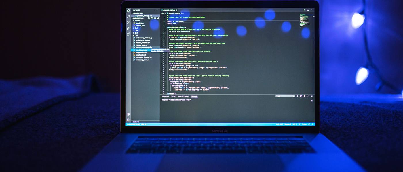 Pantalla de laptop con código de programación iluminado en azul, desarrollo de app en curso