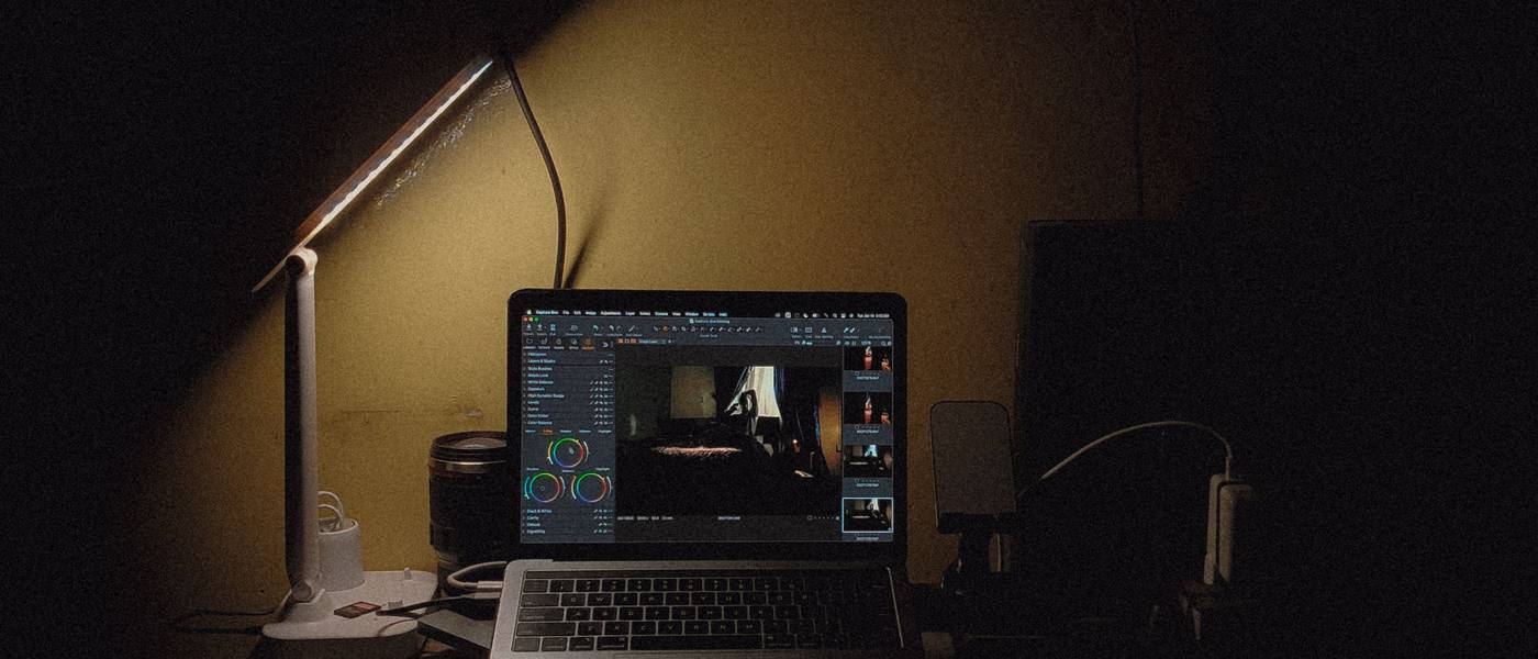 Estación de trabajo de noche con laptop encendida y lámpara, taller digital de la agencia