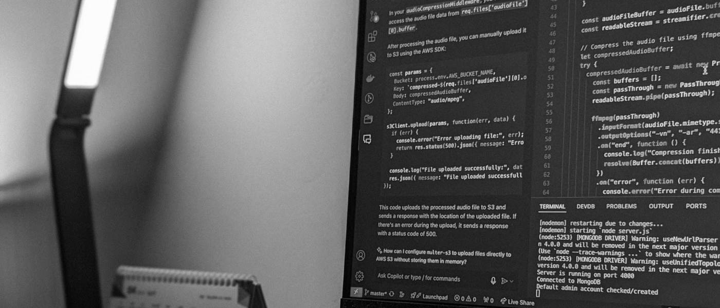 Estación de trabajo de desarrollo con código en pantalla, teclado mecánico y laptop, ambiente de la agencia